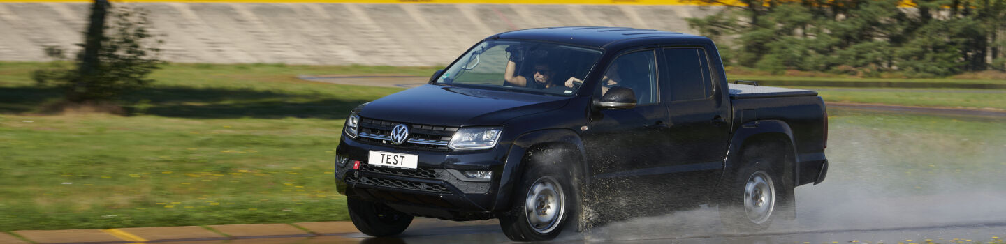 Ein schwarzer Pick Up fährt auf nasser Fahrbahn.
