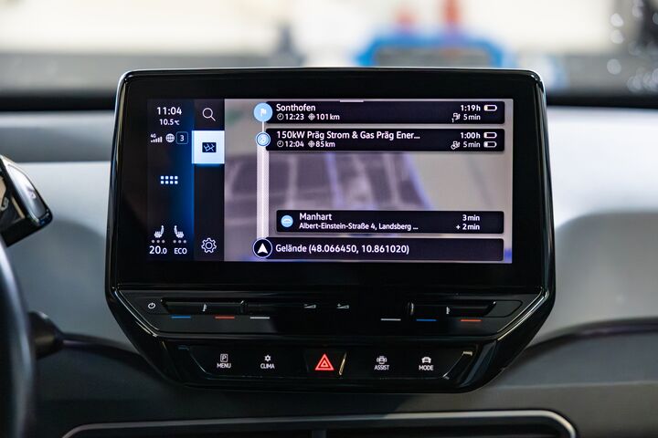 Auf dem Bild sieht man das Display in einem Auto. Auf dem Bildschirm ist die Planung einer Navigation zu sehen.