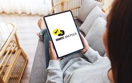 Junge Frau sitzt auf dem Sofa mit ihrem Tablet in der Hand.