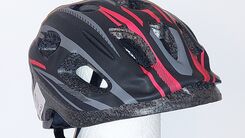 Kinderfahrradhelm in den Farben schwarz, grau, rot, isoliert vor grauem Hintergrund.