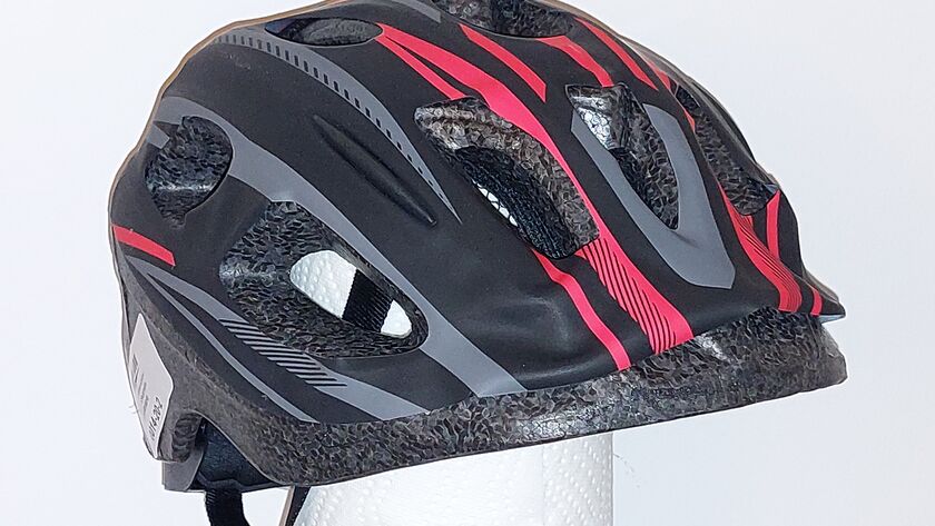 Kinderfahrradhelm in den Farben schwarz, grau, rot, isoliert vor grauem Hintergrund.