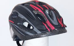 Kinderfahrradhelm in den Farben schwarz, grau, rot, isoliert vor grauem Hintergrund.