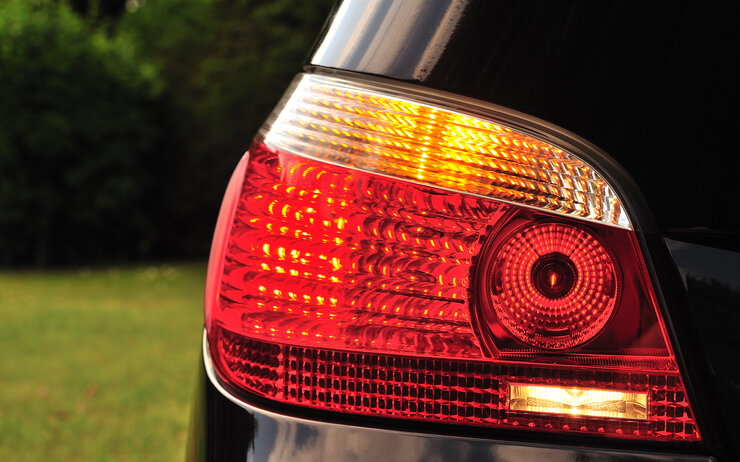 Eine nahe, große Aufnahme von einem schwarzen Auto, nur der Blinker und Scheinwerfer sind sichtbar.