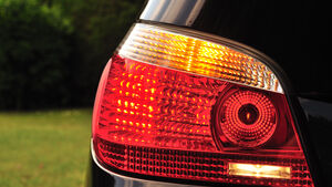 Eine nahe, große Aufnahme von einem schwarzen Auto, nur der Blinker und Scheinwerfer sind sichtbar.