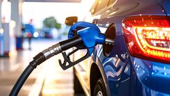 Ein blaues Auto an der Zapfsäule.