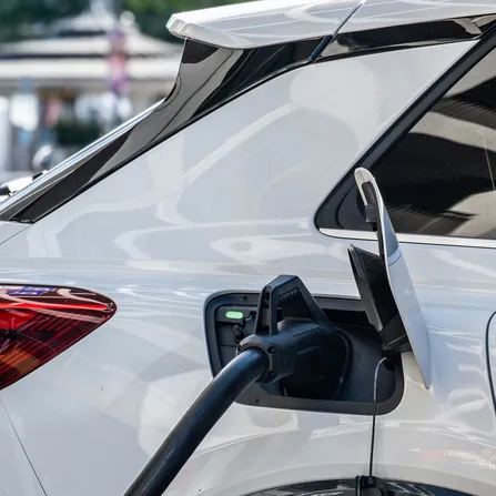 Ein weißes Elektroauto lädt an einer Ladesäule.