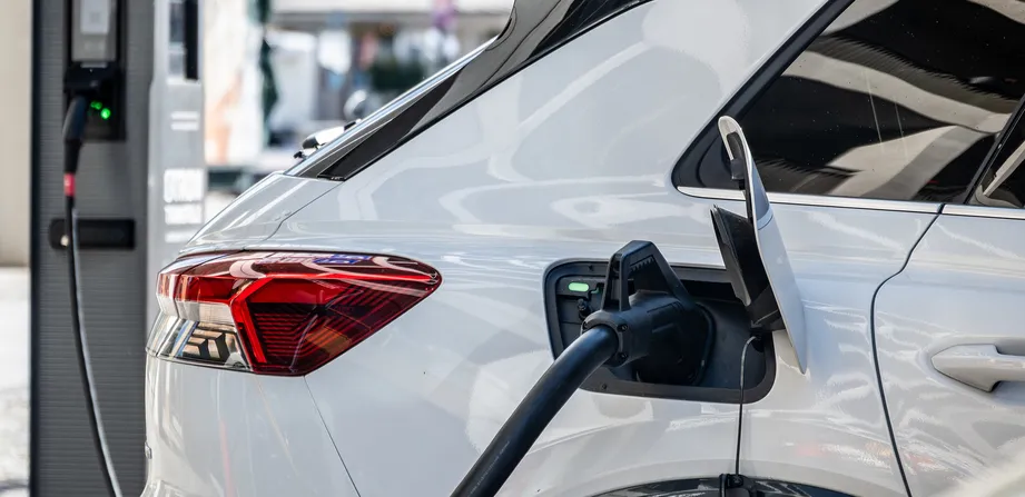 Ein weißes Elektroauto lädt an einer Ladesäule.