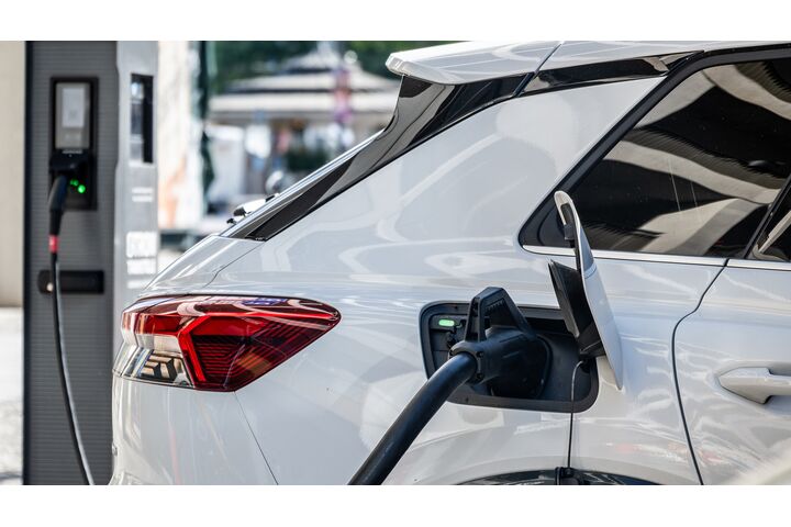 Ein weißes Elektroauto lädt an einer Ladesäule.