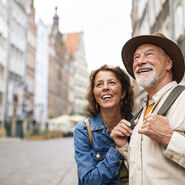 Porträt eines glücklichen Seniorenpaares, das als Touristen im Freien in einer historischen Altstadt unterwegs ist.