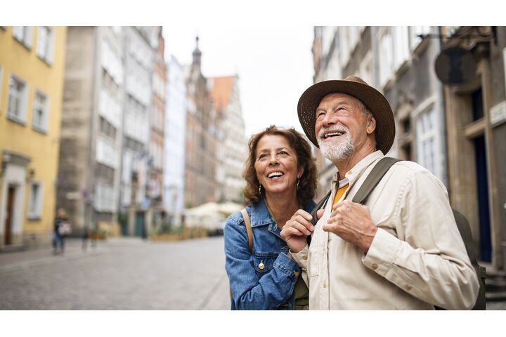 Porträt eines glücklichen Seniorenpaares, das als Touristen im Freien in einer historischen Altstadt unterwegs ist.