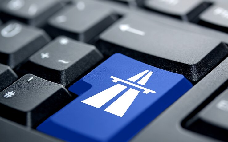 Computer-Tastatur mit blauer Taste und Autobahn-Symbol für den sicheren Online-Kauf einer Vignette