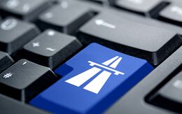 Computer-Tastatur mit blauer Taste und Autobahn-Symbol für den sicheren Online-Kauf einer Vignette