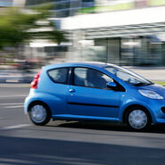 Ein blauer Kleinwagen fährt durch die Stadt