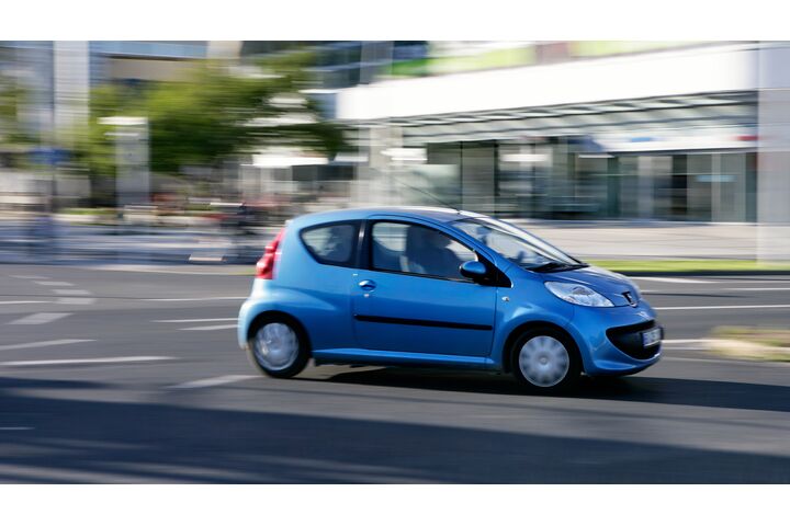 Ein blauer Kleinwagen fährt durch die Stadt