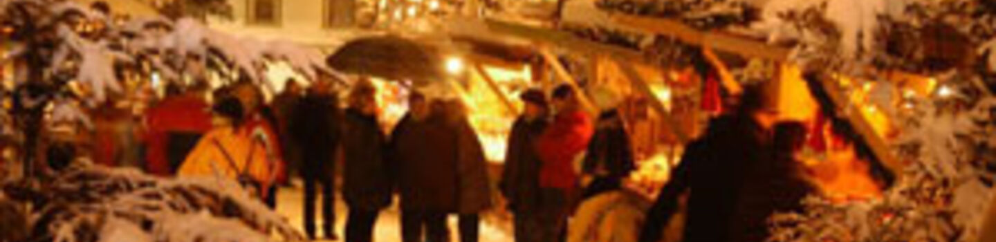 Winterlich verschneiter Adventmarkt mit weihnachtlicher Beleuchtung