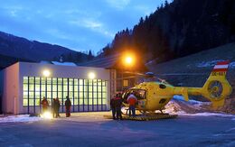 Christophorus-Hubschrauber steht vor dem Hangar am Stützpunkt Patergassen bei Dämmerung in einer Winterlandschaft.