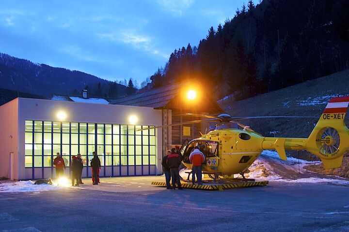 Christophorus-Hubschrauber steht vor dem Hangar am Stützpunkt Patergassen bei Dämmerung in einer Winterlandschaft.