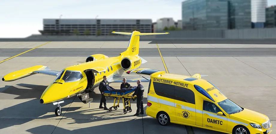 ÖAMTC Ambulanzjet und ÖAMTC Rettungsfahrzeug stehen am Flugfeld. Drei Personen in der Mitte.