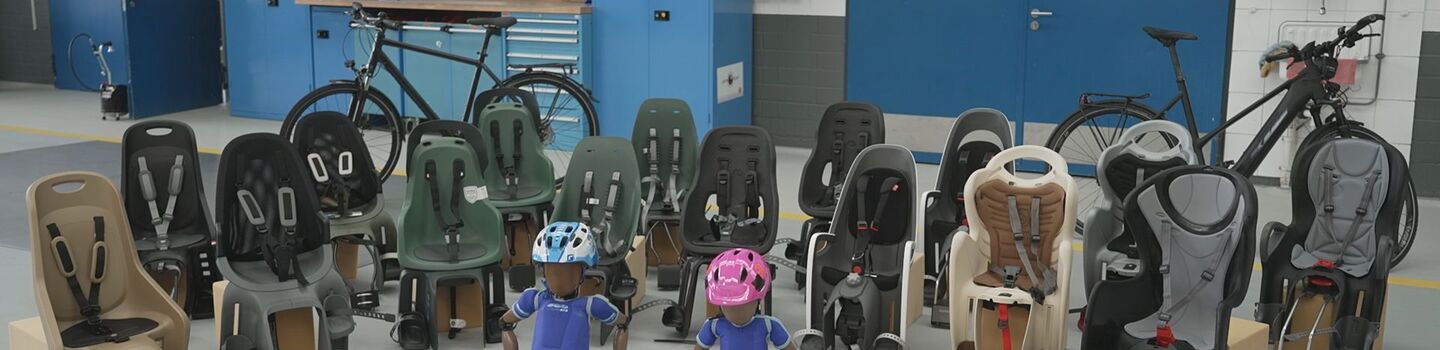 Aktuelle Fahrrad-Kindersitze im Test, aufgereiht in der Prüfhalle.