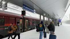 Menschen am Bahnsteig von Sankt Anton am Arlberg. Im Hintergrund ein Railjet