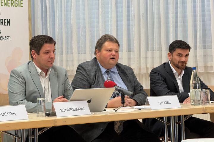 Drei Männer im Anzug sitzen an einem Tisch 