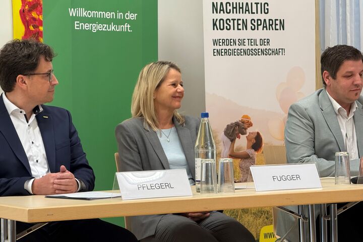 Zwei Männer im Anzug und eine blonde Frau sitzen an einem Tisch 