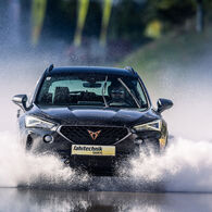 Ein Cupra der ÖAMTC Fahrtechnik fährt mit hoher Geschwindigkeit über eine nasse Fahrbahn