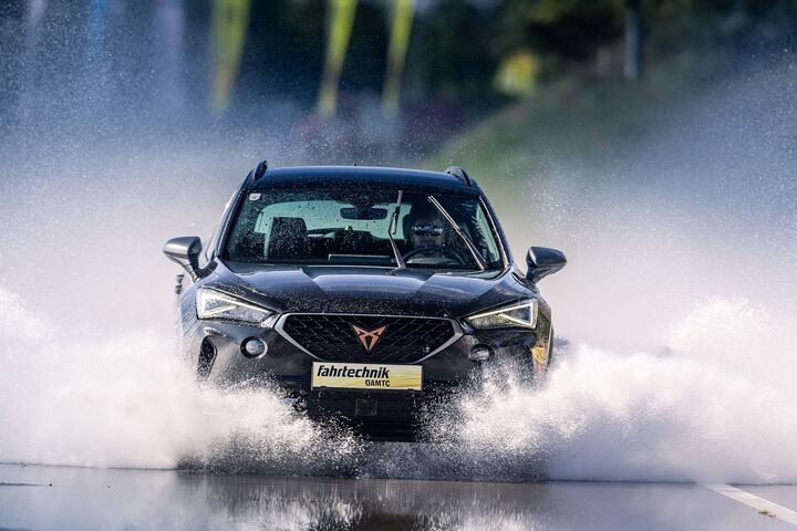 Ein Cupra der ÖAMTC Fahrtechnik fährt mit hoher Geschwindigkeit über eine nasse Fahrbahn