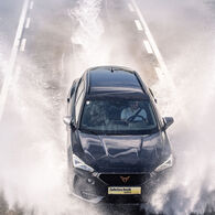 Ein Cupra der ÖAMTC Fahrtechnik fährt mit hoher Geschwindigkeit über eine nasse Fahrbahn
