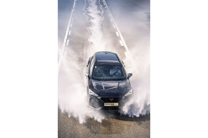Ein Cupra der ÖAMTC Fahrtechnik fährt mit hoher Geschwindigkeit über eine nasse Fahrbahn