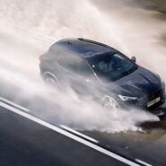 Ein Cupra der ÖAMTC Fahrtechnik fährt mit hoher Geschwindigkeit über eine nasse Fahrbahn