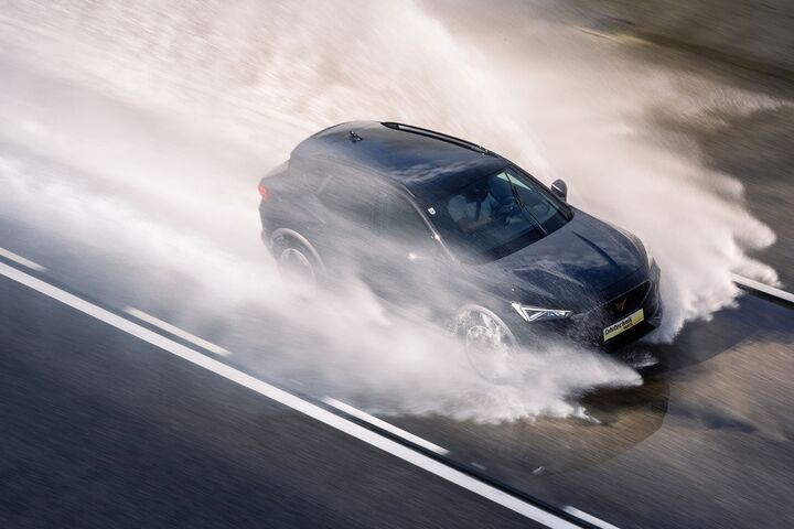 Ein Cupra der ÖAMTC Fahrtechnik fährt mit hoher Geschwindigkeit über eine nasse Fahrbahn