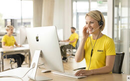 zeigt eine junge telefonierende Callcenter Mitarbeiterin in einem modernen Büro des ÖAMTC