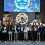 Man sieht viele Menschen leicht von oben fotografiert bei der Siegerehrung vom Camping Star 2026. Das Gruppenfoto zeigt alle Sieger:innen mit Pokalen und Awards. 