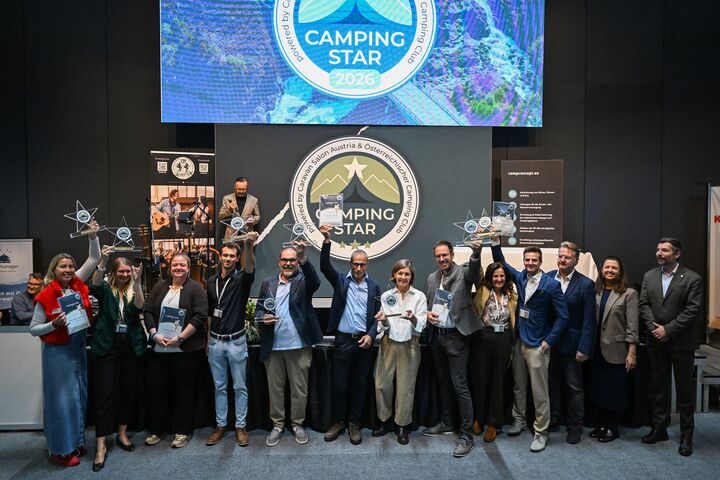 Man sieht viele Menschen leicht von oben fotografiert bei der Siegerehrung vom Camping Star 2026. Das Gruppenfoto zeigt alle Sieger:innen mit Pokalen und Awards. 