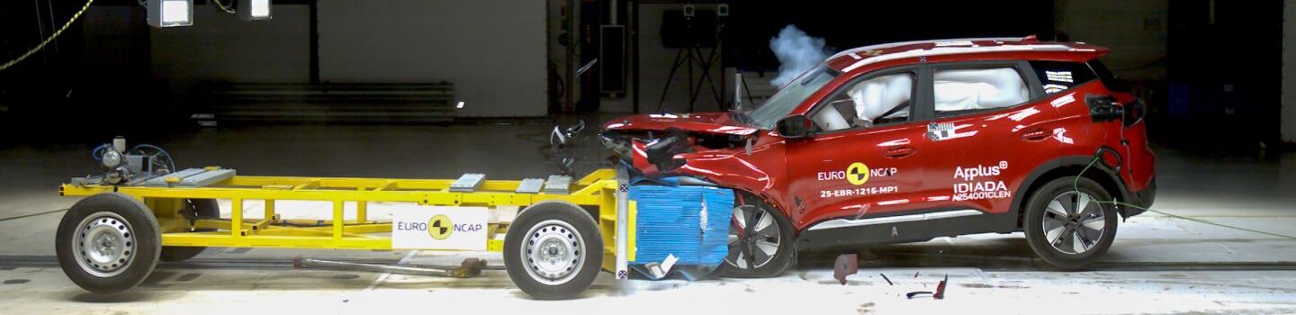 Rechts ein rotes Auto in einer Testhalle. Ein gelber Testwagen fährt von links in das Fahrzeug direkt in die Motorhaube.