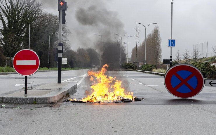 Blockierte Straße: umgestürzte Schilder, Stoppsignal und brennende Reifen während eines Streiks