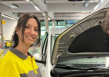 Das Bild zeigt eine Frau mit Braunen Haaren, die ein ÖAMTC-Oberteil trägt un in einer Werkstatt steht.