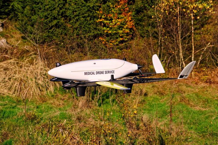 Eine Drohne des Projekts Medical Drone Service bei einem Testflug in Bodennähe, im Hintergrund sind man eine Wiese.