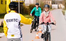 Zwei ältere Personen üben mit dem E-Bike Kurvenfahren. Im Vordergrund gibt die ÖAMTC-Instruktorin Anweisungen.