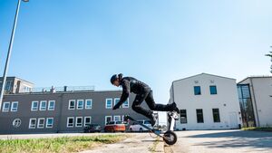 Ein Mann stürzt mit seinem E-Scooter über einen Bordstein.
