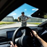 Aus dem Auto heraus sieht man einen Mann auf einem E-Scooter, der wohl im nächsten Moment frontal mit dem Fahrzeug kollidieren wird