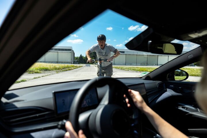 Aus dem Auto heraus sieht man einen Mann auf einem E-Scooter, der wohl im nächsten Moment frontal mit dem Fahrzeug kollidieren wird