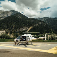Im Bild ist der Hubschrauber der Experience World Saalfelden zu sehen, auf einem Landeplatz, vor einer malerischen Alpenkulisse