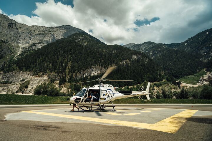 Im Bild ist der Hubschrauber der Experience World Saalfelden zu sehen, auf einem Landeplatz, vor einer malerischen Alpenkulisse