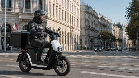 Ein Fahrer, der mit dem E-Moped mit Gepäck (25 km/h) in der Stadt unterwegs ist.