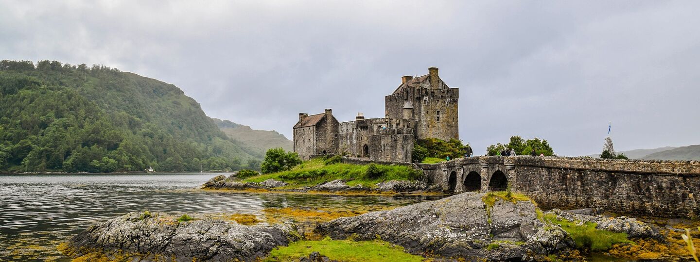 Malerischer Blick auf das Eilean Donan Castle in den schottischen Highlands bei Nebel, umgeben von Wasser und sanften Hügeln