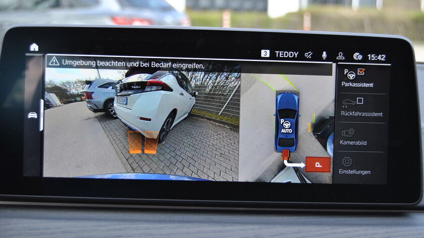 Screen von einem Einparkassistenten im Cockpit, darauf sichtbar das Heck von zwei Autos am Parkplatz.