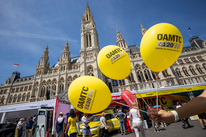 Drei Gelbe ÖAMTC Luftballone auf den Wiener Elektro Tagen 2026 mit dem Wiener Rathaus und Messeständen im Hintergrund