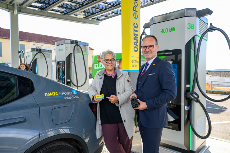Auf dem Bild ist links das hintere Teil eines Autos zu sehen mit einem Sticker von ÖAMTC ePower.Business. Daneben steht eine Frau, Marcella Kral, die eine ÖAMTC Ladekarte in der Hand hat. Neben ihr steht ÖAMTC Landesdirektor Harald Großauer.